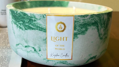 Marble-patterned candle with 'Light of the World' label on a wooden surface