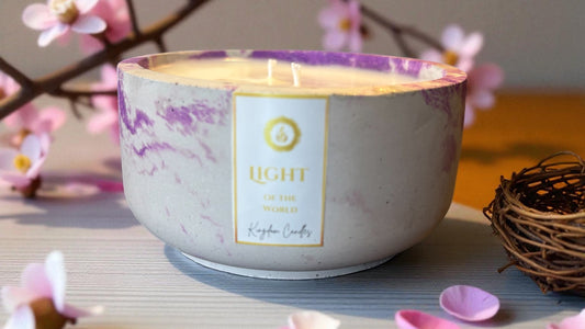 Candle in a decorative bowl with pink floral elements on a light surface