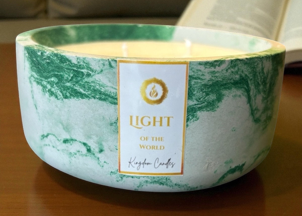 Marble-patterned candle with 'Light of the World' label on a wooden surface